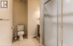 Bathroom featuring toilet, vanity, tile patterned flooring, and a shower with door - 