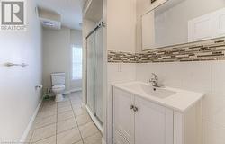 Bathroom featuring toilet, tile patterned floors, an enclosed shower, and vanity - 