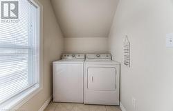 Laundry room with light tile patterned floors and washing machine and dryer - 