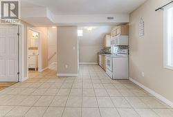 Kitchen with white appliances, light brown cabinets, sink, backsplash, and light tile patterned floors - 