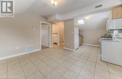 Kitchen with light tile patterned floors, light brown cabinets, white appliances, and vaulted ceiling - 