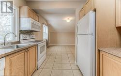 Kitchen with light brown cabinets, sink, and white appliances - 