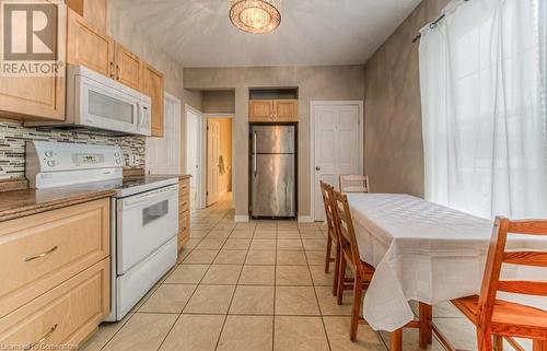 Kitchen with tile countertops, decorative backsplash, white appliances, light brown cabinets, and light tile patterned floors - 67 Wellington Street N, Kitchener, ON - Indoor Photo Showing Kitchen