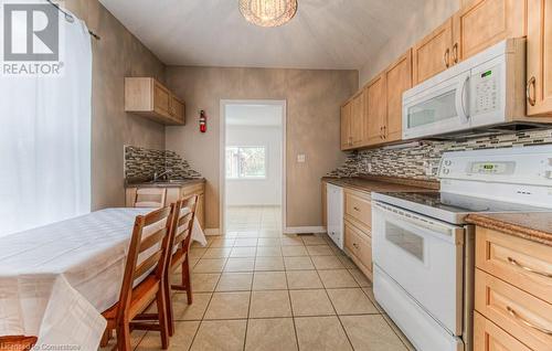 Kitchen with light brown cabinetry, white appliances, tasteful backsplash, and light tile patterned flooring - 67 Wellington Street N, Kitchener, ON - Indoor Photo Showing Kitchen