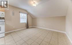 Additional living space featuring vaulted ceiling and light tile patterned flooring - 