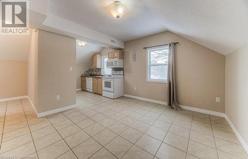 Kitchen featuring vaulted ceiling, backsplash, sink, white appliances, and light tile patterned floors - 67 Wellington Street N, Kitchener, ON - Indoor