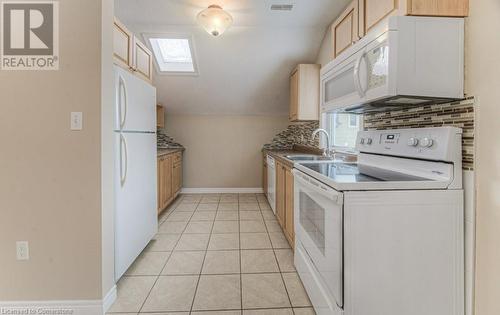 Kitchen featuring light brown cabinets, sink, white appliances, and light tile patterned flooring - 67 Wellington Street N, Kitchener, ON - Indoor Photo Showing Laundry Room