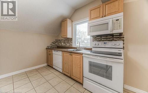 Kitchen with white appliances, lofted ceiling, sink, backsplash, and light tile patterned flooring - 67 Wellington Street N, Kitchener, ON - Indoor Photo Showing Kitchen