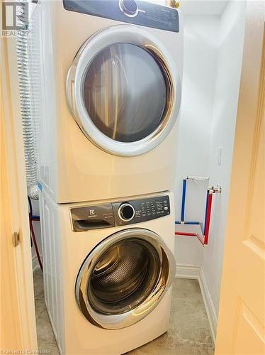 Laundry room featuring stacked washing maching and dryer - 255 Woolwich Street Unit# 203, Waterloo, ON - Indoor Photo Showing Laundry Room