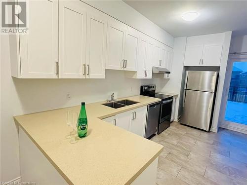 Kitchen featuring white cabinetry, sink, and appliances with stainless steel finishes - 255 Woolwich Street Unit# 203, Waterloo, ON - Indoor Photo Showing Kitchen With Double Sink