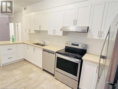 Kitchen featuring white cabinetry, appliances with stainless steel finishes, sink, and light tile patterned flooring - 255 Woolwich Street Unit# 203, Waterloo, ON - Indoor Photo Showing Kitchen With Double Sink