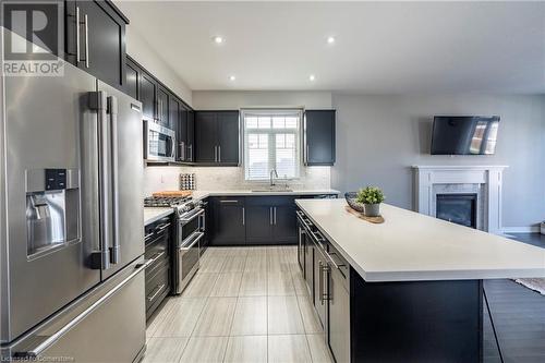 Kitchen with tasteful backsplash, sink, a center island, stainless steel appliances, and a premium fireplace - 219 Falconridge Drive, Kitchener, ON - Indoor Photo Showing Kitchen With Stainless Steel Kitchen With Upgraded Kitchen