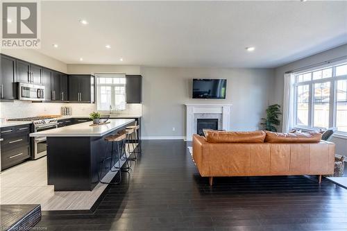 Kitchen with stainless steel appliances, a center island, wood-type flooring, and a breakfast bar area - 219 Falconridge Drive, Kitchener, ON - Indoor With Fireplace