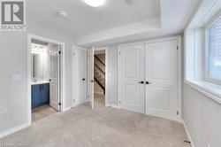 Unfurnished bedroom featuring sink, ensuite bath, a textured ceiling, light colored carpet, and a closet - 