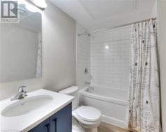 Full bathroom featuring hardwood / wood-style flooring, vanity, toilet, and shower / bath combo - 