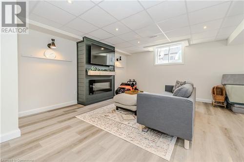 Living room with a large fireplace, a paneled ceiling, and light hardwood / wood-style floors - 12 Hardcastle Place, Cambridge, ON - Indoor With Fireplace