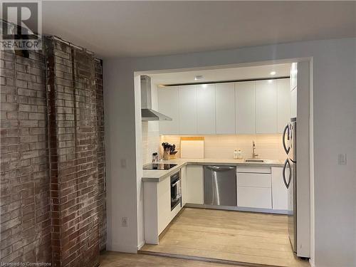 Kitchen featuring white cabinetry, dishwasher, wall chimney range hood, and wall oven - 67 Louisa Street, Kitchener, ON - Indoor Photo Showing Kitchen