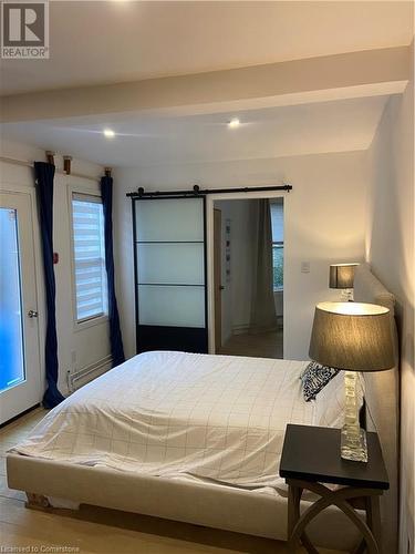 Bedroom with beam ceiling, a barn door, and baseboard heating - 67 Louisa Street, Kitchener, ON - Indoor Photo Showing Bedroom