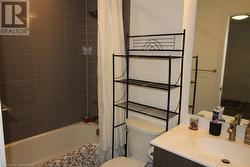 Full bathroom with vanity, shower / bath combination with curtain, and toilet - 