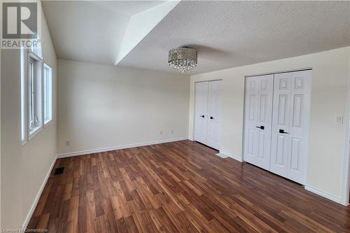 Unfurnished bedroom featuring ceiling fan, dark wood-type flooring, two closets, and a textured ceiling - 39 Bridlewreath Street, Kitchener, ON - Indoor Photo Showing Other Room