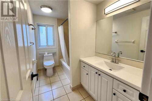 Full bathroom with shower / bathtub combination with curtain, tile patterned floors, vanity, and toilet - 39 Bridlewreath Street, Kitchener, ON - Indoor Photo Showing Bathroom