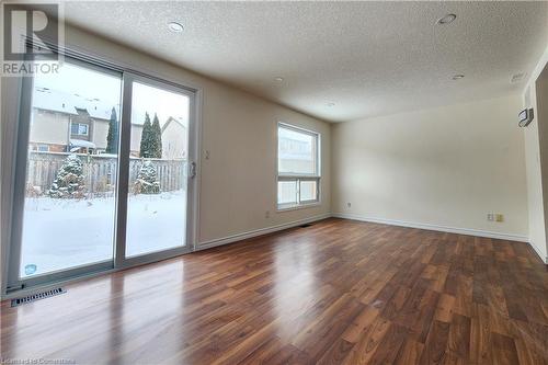 Empty room featuring dark wood-type flooring and a textured ceiling - 39 Bridlewreath Street, Kitchener, ON - Indoor Photo Showing Other Room