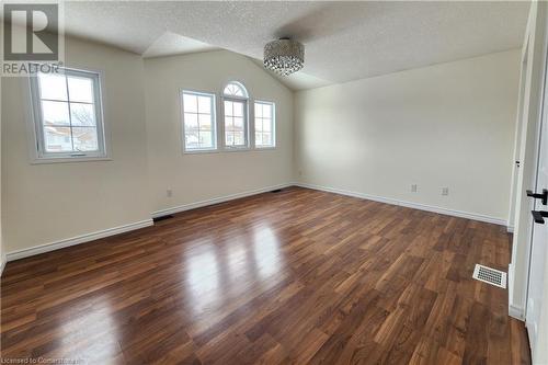 Empty room featuring lofted ceiling, dark hardwood / wood-style floors, a textured ceiling, and a wealth of natural light - 39 Bridlewreath Street, Kitchener, ON - Indoor Photo Showing Other Room