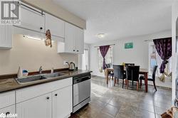 Kitchen with dishwasher, sink, white cabinets, and a textured ceiling - 