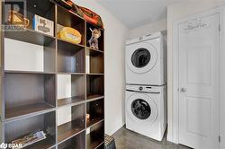 Clothes washing area featuring stacked washing maching and dryer and dark tile patterned flooring - 