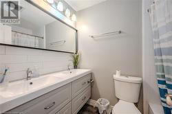 Bathroom featuring toilet, curtained shower, vanity, and decorative backsplash - 