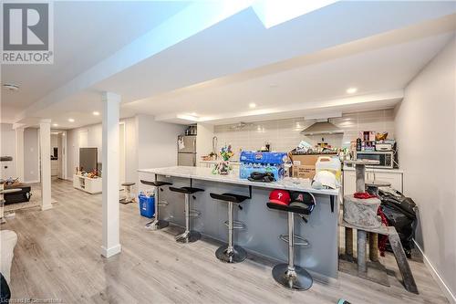 Kitchen with light wood-type flooring, stainless steel fridge, a kitchen breakfast bar, island exhaust hood, and backsplash - 82 Conway Drive, Kitchener, ON - Indoor Photo Showing Other Room