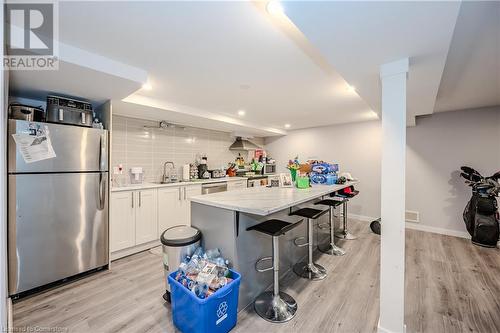 Kitchen featuring stainless steel appliances, white cabinets, a kitchen bar, decorative backsplash, and wall chimney exhaust hood - 82 Conway Drive, Kitchener, ON - Indoor