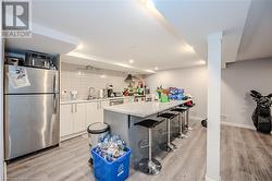 Kitchen featuring stainless steel appliances, white cabinets, a kitchen bar, decorative backsplash, and wall chimney exhaust hood - 