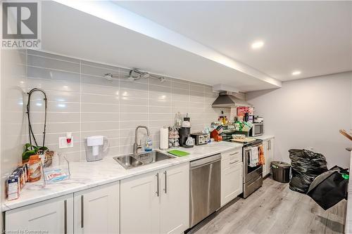 Kitchen featuring white cabinetry, sink, backsplash, stainless steel appliances, and wall chimney exhaust hood - 82 Conway Drive, Kitchener, ON - Indoor