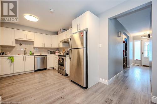 Kitchen with sink, appliances with stainless steel finishes, tasteful backsplash, light hardwood / wood-style floors, and white cabinets - 82 Conway Drive, Kitchener, ON - Indoor Photo Showing Kitchen