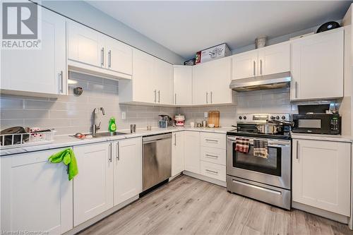 Kitchen with sink, stainless steel appliances, light hardwood / wood-style floors, decorative backsplash, and white cabinets - 82 Conway Drive, Kitchener, ON - Indoor Photo Showing Kitchen