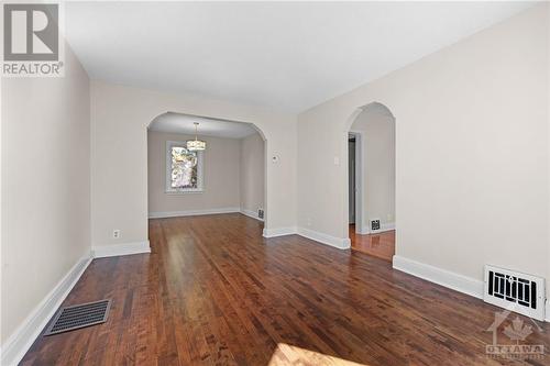 Lovely character arched doorways into living and dining rooms, which are anchored by polished hardwood floors creating a warm, cozy atmosphere. - 11 Gilchrist Avenue, Ottawa, ON - Indoor Photo Showing Other Room