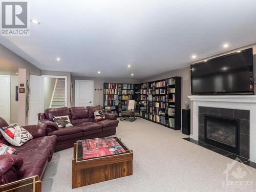 You will feel like you are in a real movie theatre.  Surround sound speakers, woofer and TV come with the house.  You just need to bring in your reclining chairs and start a movie.  Bookcases can - 322 Tucana Way, Ottawa, ON - Indoor Photo Showing Living Room With Fireplace