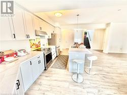 Kitchen featuring a kitchen island, decorative light fixtures, white cabinetry, stainless steel appliances, and light hardwood / wood-style flooring - 