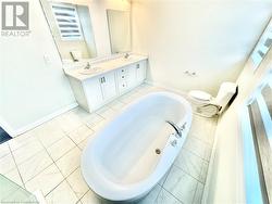 Bathroom with vanity, a tub to relax in, and toilet - 