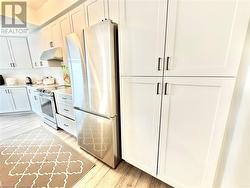 Kitchen with light hardwood / wood-style flooring, white cabinets, and appliances with stainless steel finishes - 