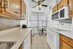 Kitchen featuring white appliances, light tile patterned flooring, a textured ceiling, and tasteful backsplash - 