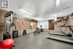 Exercise room featuring a textured ceiling and brick wall - 