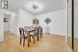 Dining area with a textured ceiling, a notable chandelier, and light hardwood / wood-style flooring - 