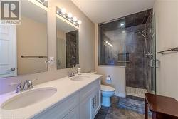 Bathroom with vanity, a shower with shower door, toilet, and tile patterned flooring - 