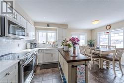 Kitchen featuring appliances with stainless steel finishes, white cabinets, a wealth of natural light, backsplash, and sink - 