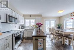 Kitchen with stainless steel appliances, sink, backsplash, wood counters, and white cabinets - 