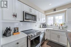 Kitchen with white cabinets, sink, stainless steel appliances, and decorative backsplash - 