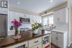 Kitchen featuring wooden counters, white cabinetry, and stainless steel appliances - 