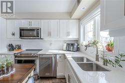 Kitchen featuring appliances with stainless steel finishes, sink, white cabinetry, and backsplash - 